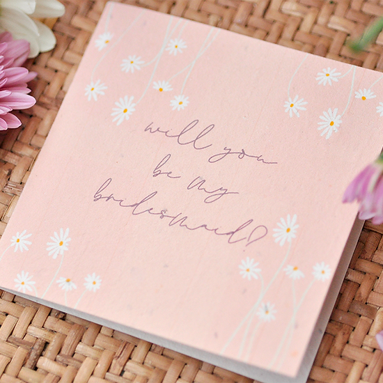 Nurturing Nature Cards plantable bridesmaid invitation with daisies on a woven surface.