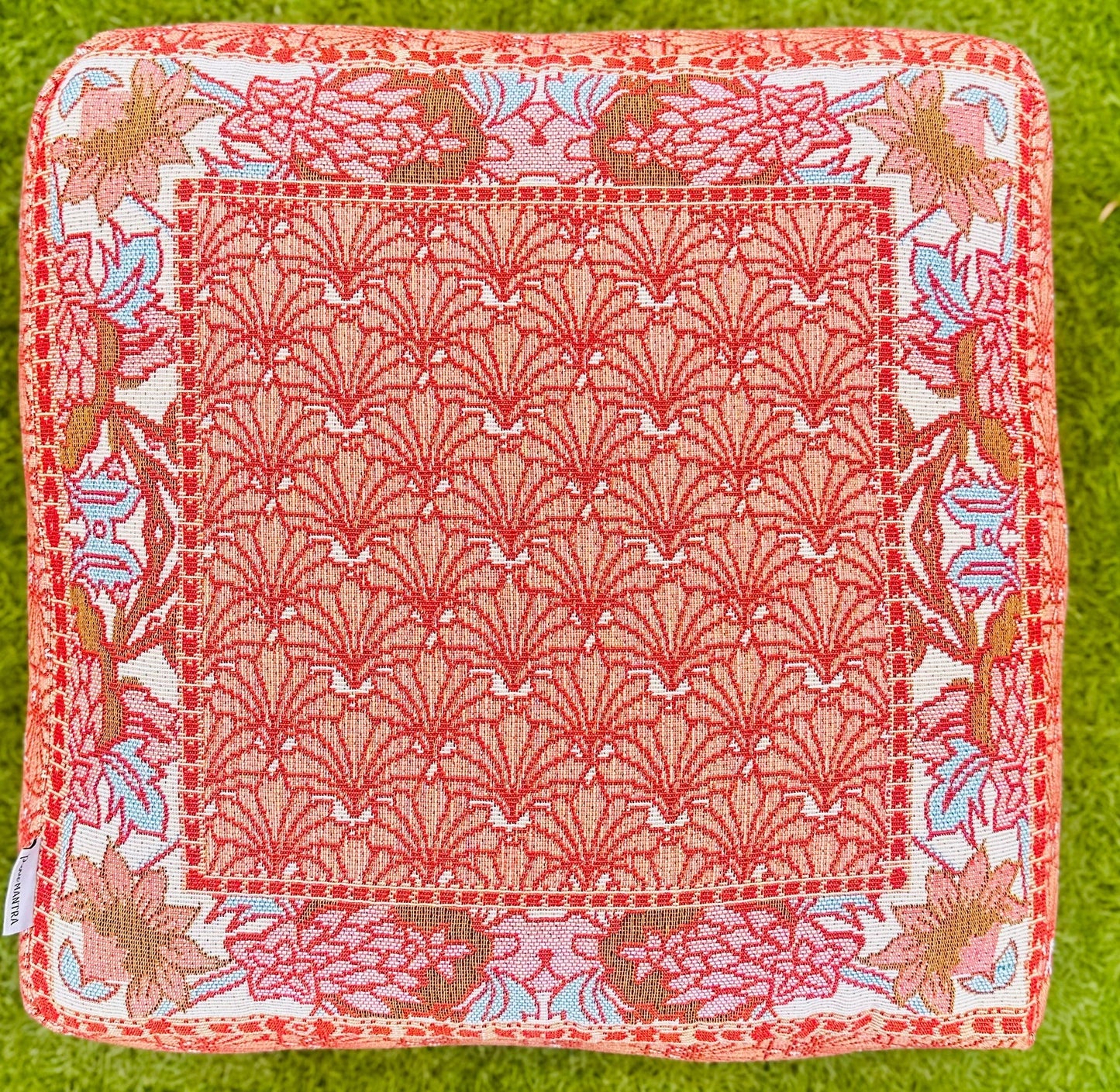 Picnic Mantra - Kaelyn Floor Cushion with vibrant Australian botanical design in pink, rusty red, and pale blue tones on grass.