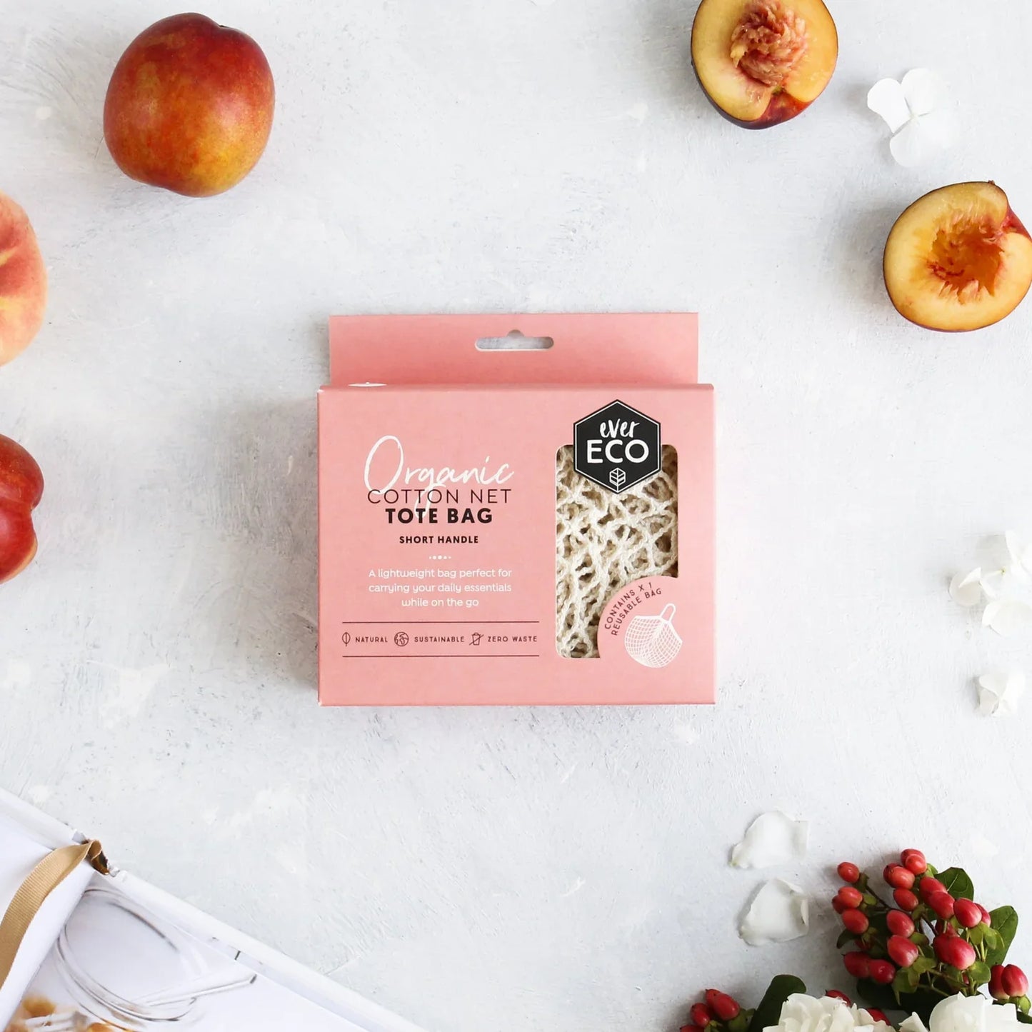 Ever Eco organic cotton net tote bag with short handle in packaging, surrounded by fruit and flowers.
