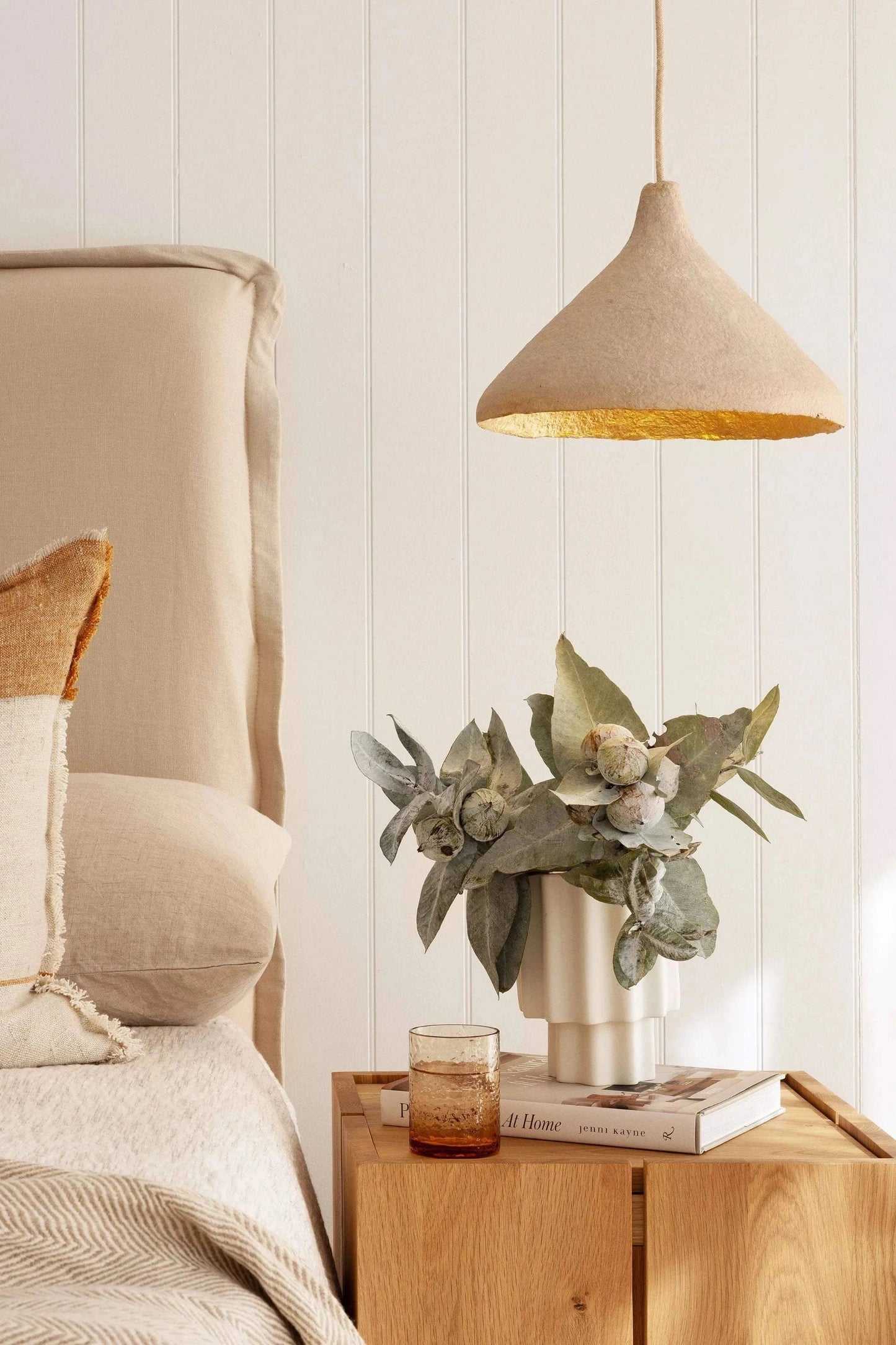 Her Hands - Classic Cone Pendant Light with scalloped edge, handmade from recycled magazines, hanging in a cozy bedroom setting.