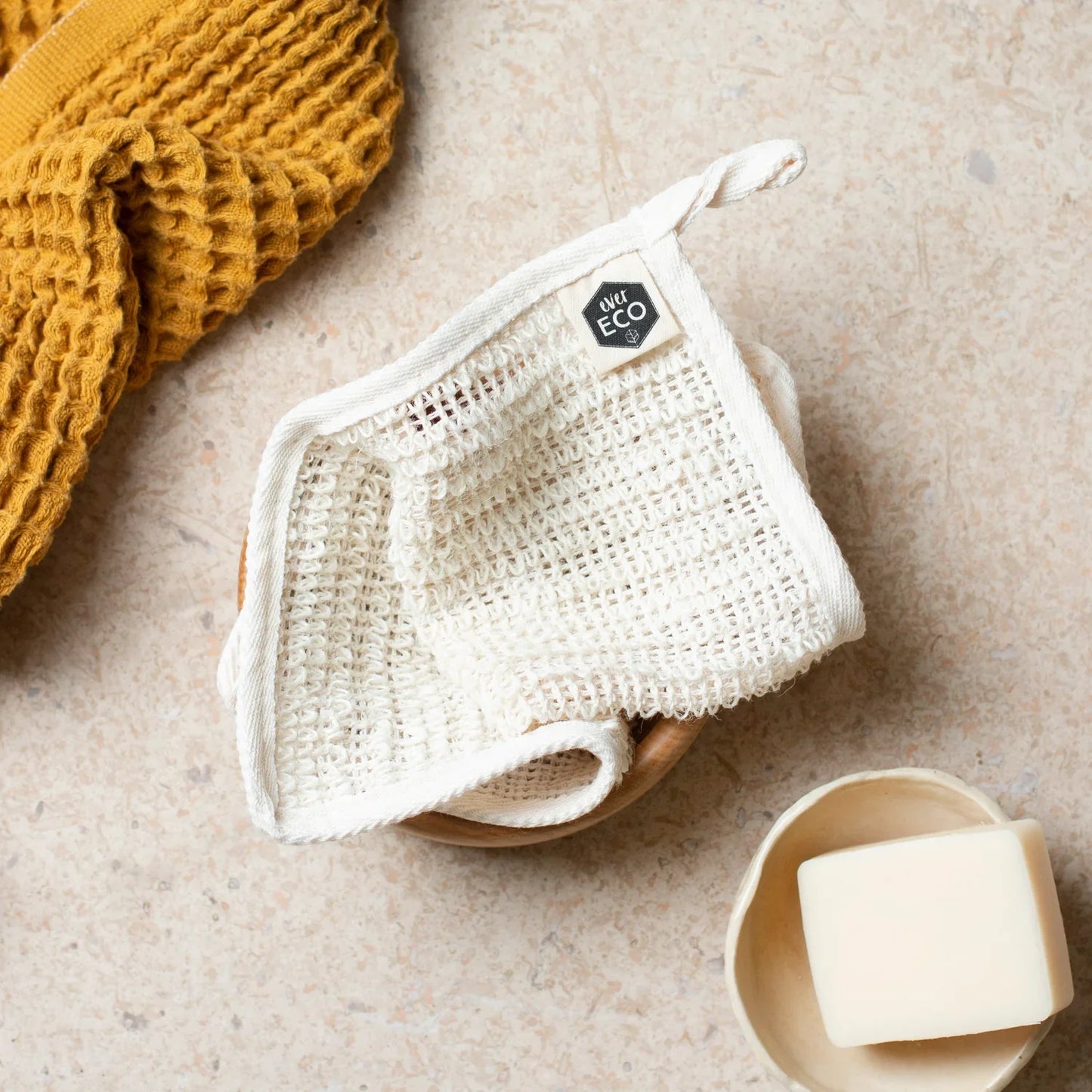 Eco-friendly exfoliating body cloth with bamboo handle and sisal bristles, featuring an ergonomic design.