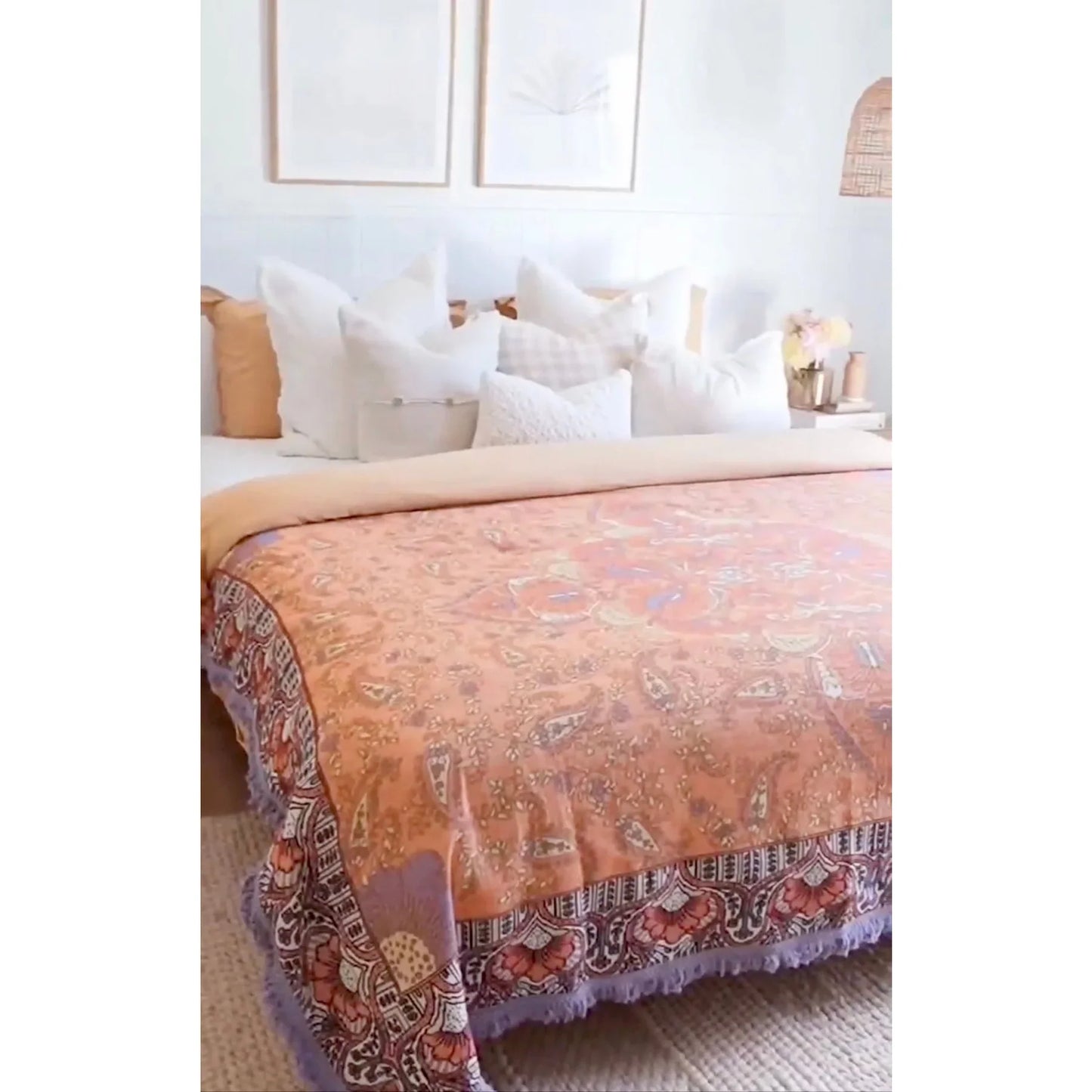 Picnic Mantra Mila Picnic Rug on bed with pastel purples, coral pinks, paisleys, and tassel edges.