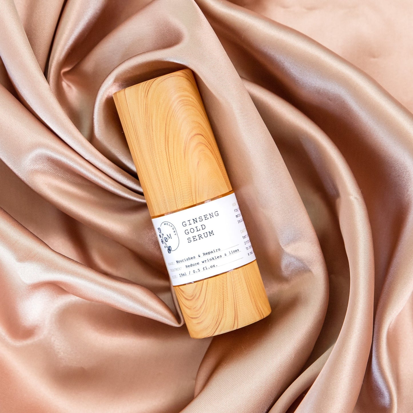 Melvory Ginseng Gold Serum bottle on silky fabric background.