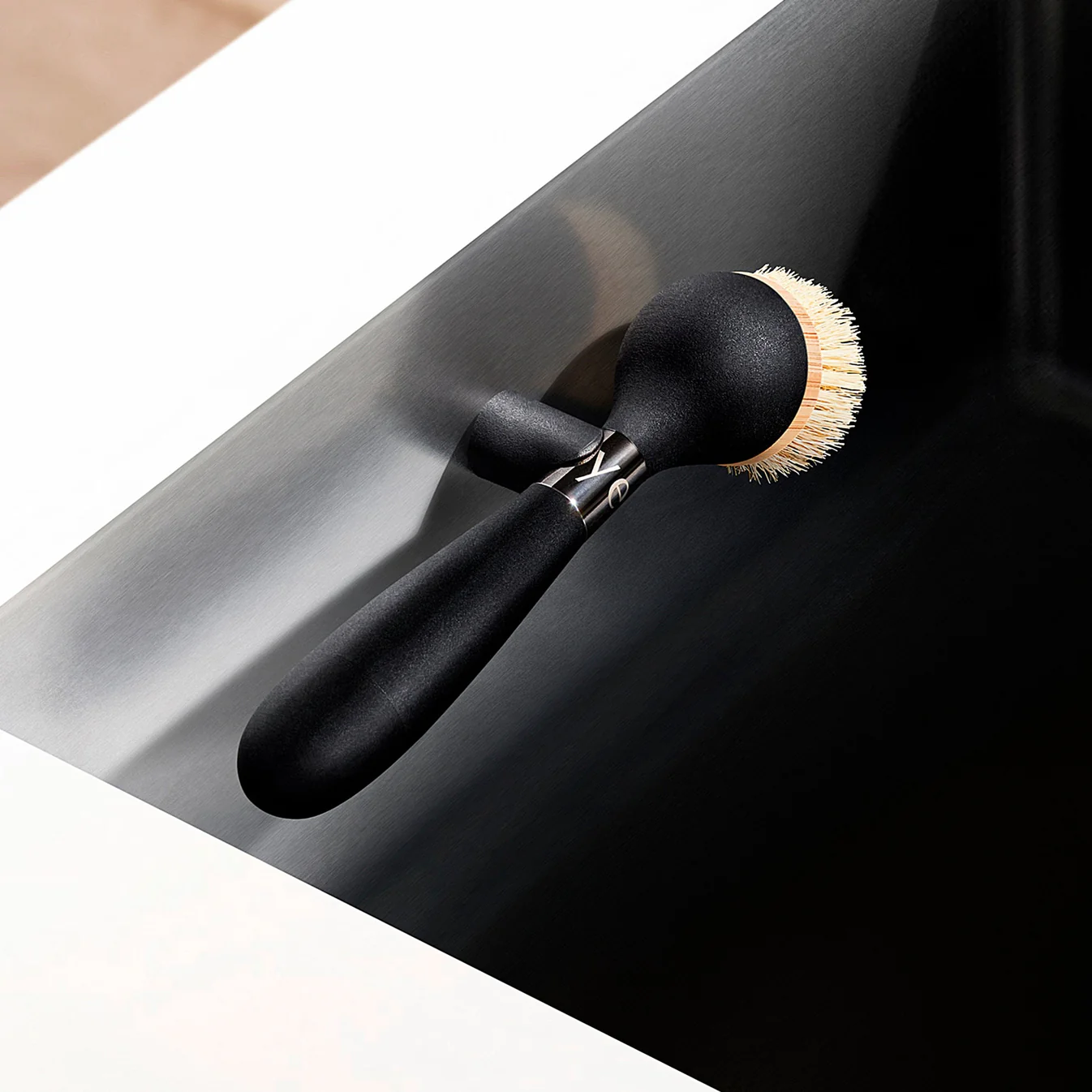 Yesēco The One Brush with black handle and natural sisal bristles on magnetic stand in sink.