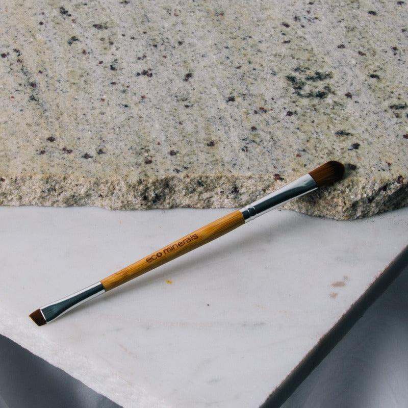Eco Minerals Eco Duo Brush on stone surface, double-sided vegan makeup tool.