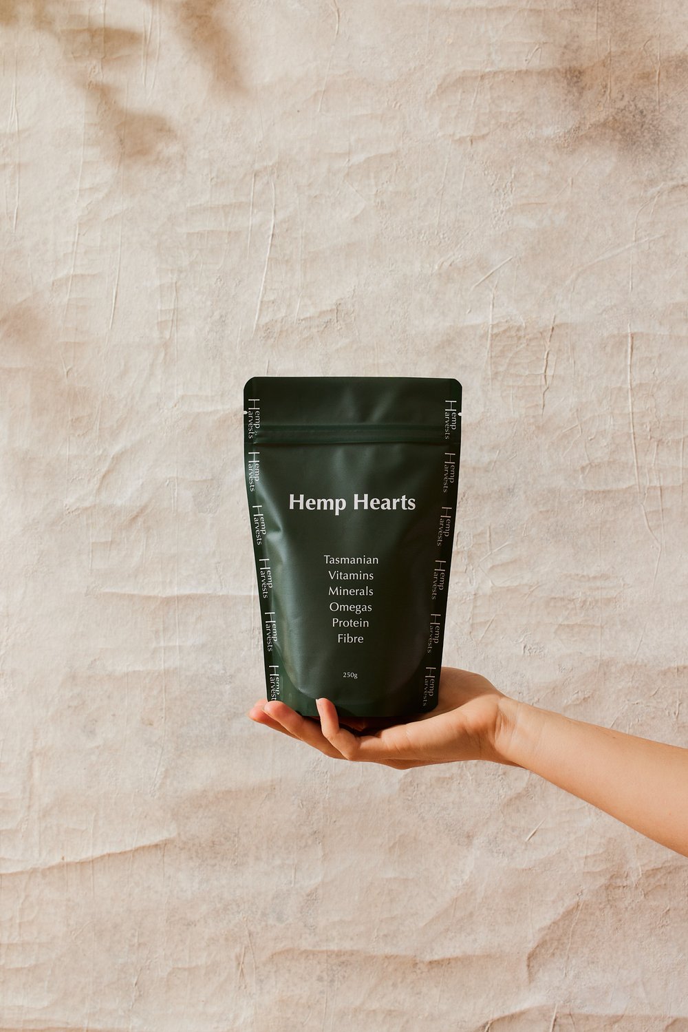 Hemp Harvests - Hemp Seed (Hearts) packaging held in hand against textured background.