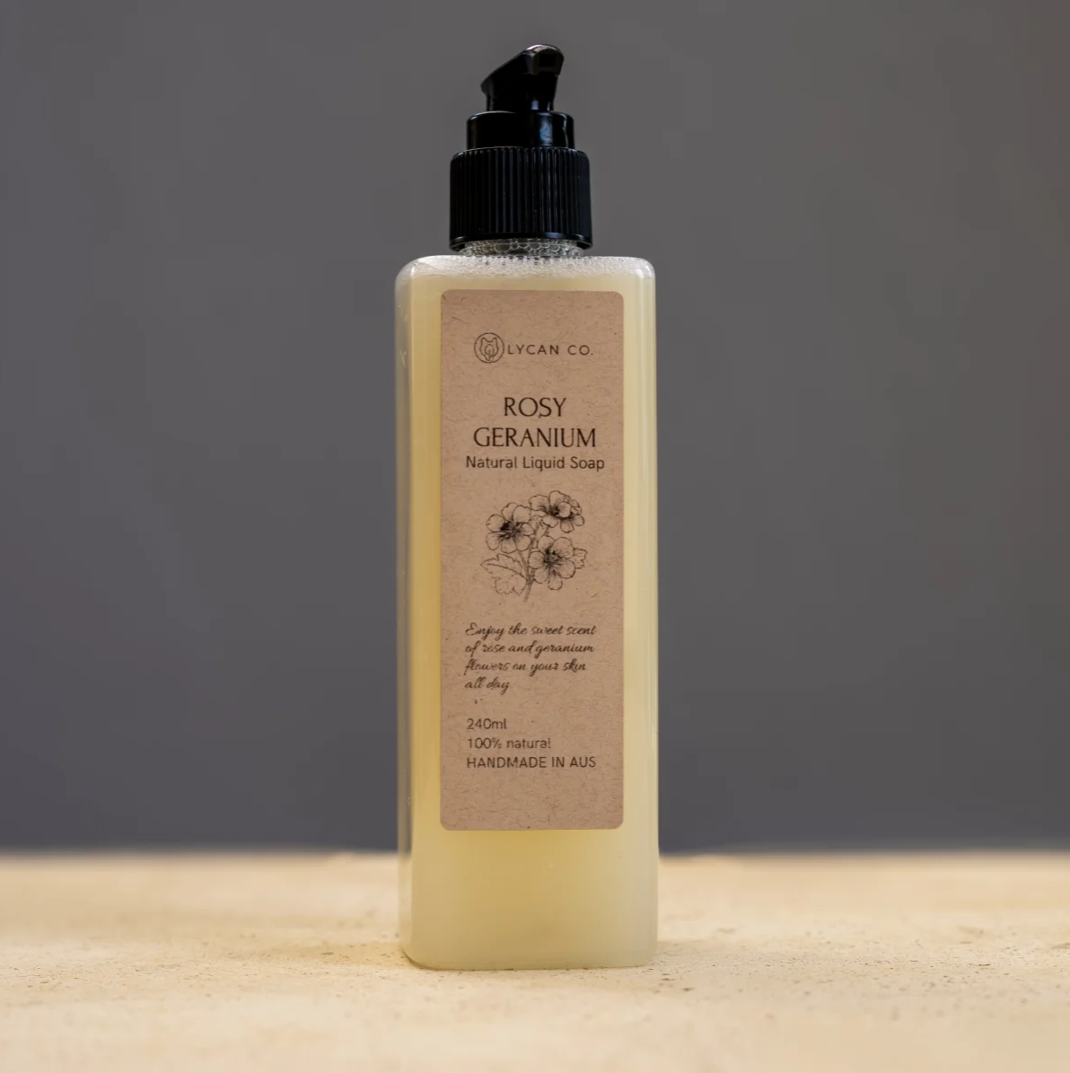 Lycan Co Rosy Geranium Liquid Soap in a dispenser bottle on wooden surface.