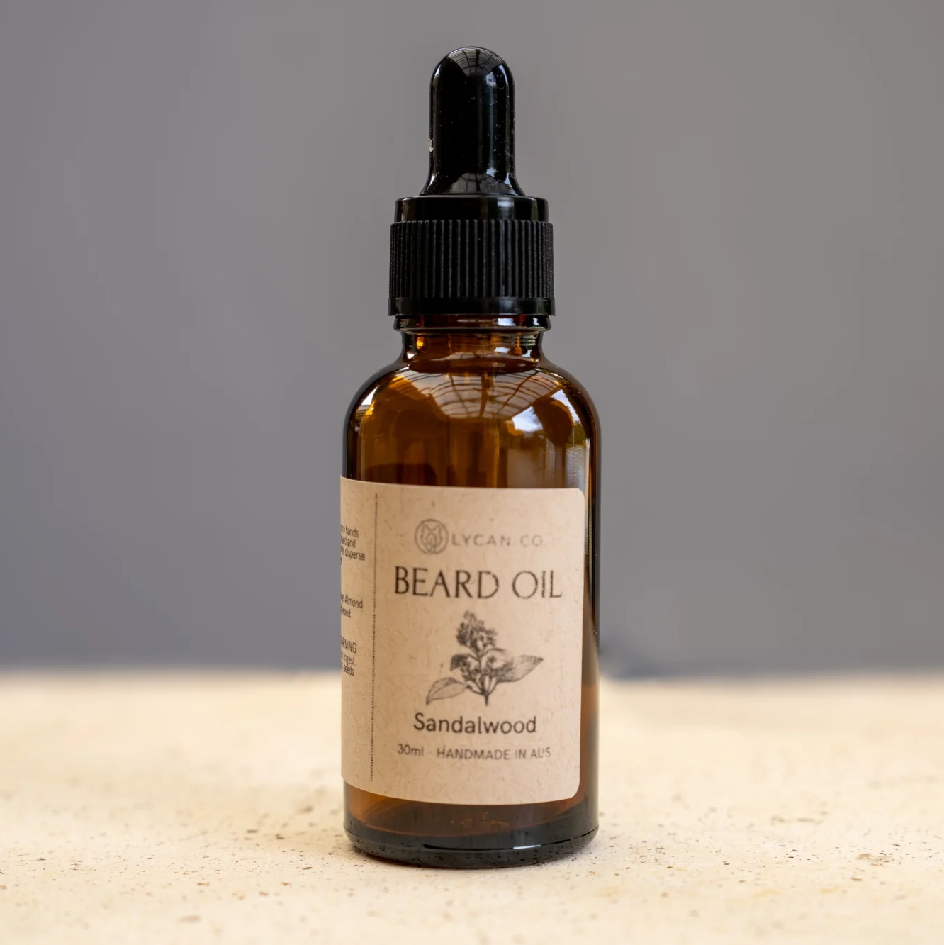 Lycan Co Sandalwood Beard Oil bottle with dropper on a beige surface.