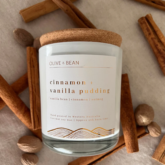 Olive & Bean cinnamon and vanilla pudding scented candle with natural coconut soy wax and wood wick surrounded by cinnamon sticks and nutmeg.