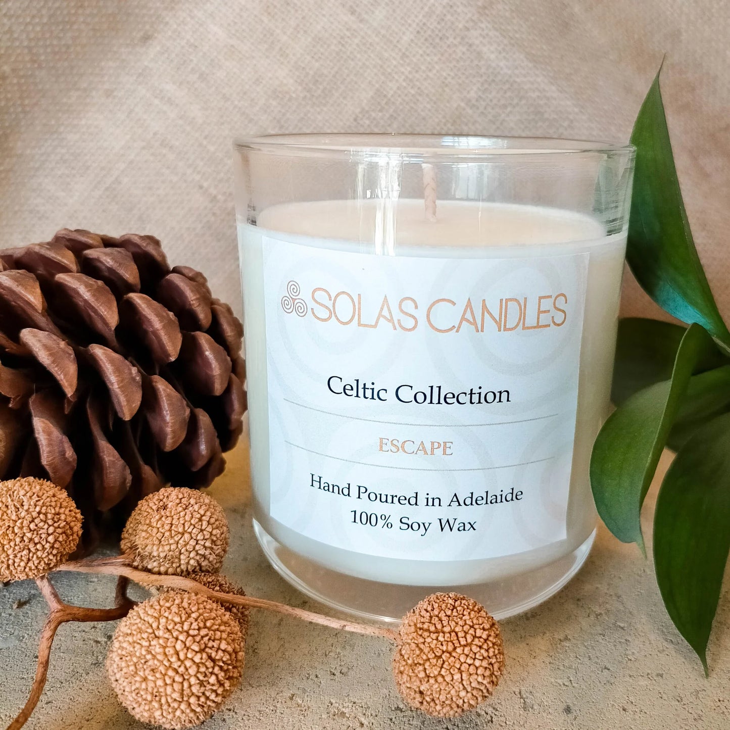 Solas Candles - Celtic Collection, Escape with pinecones and greenery background.