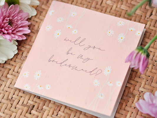 Nurturing Nature Cards plantable bridesmaid invitation with daisies on a woven surface.