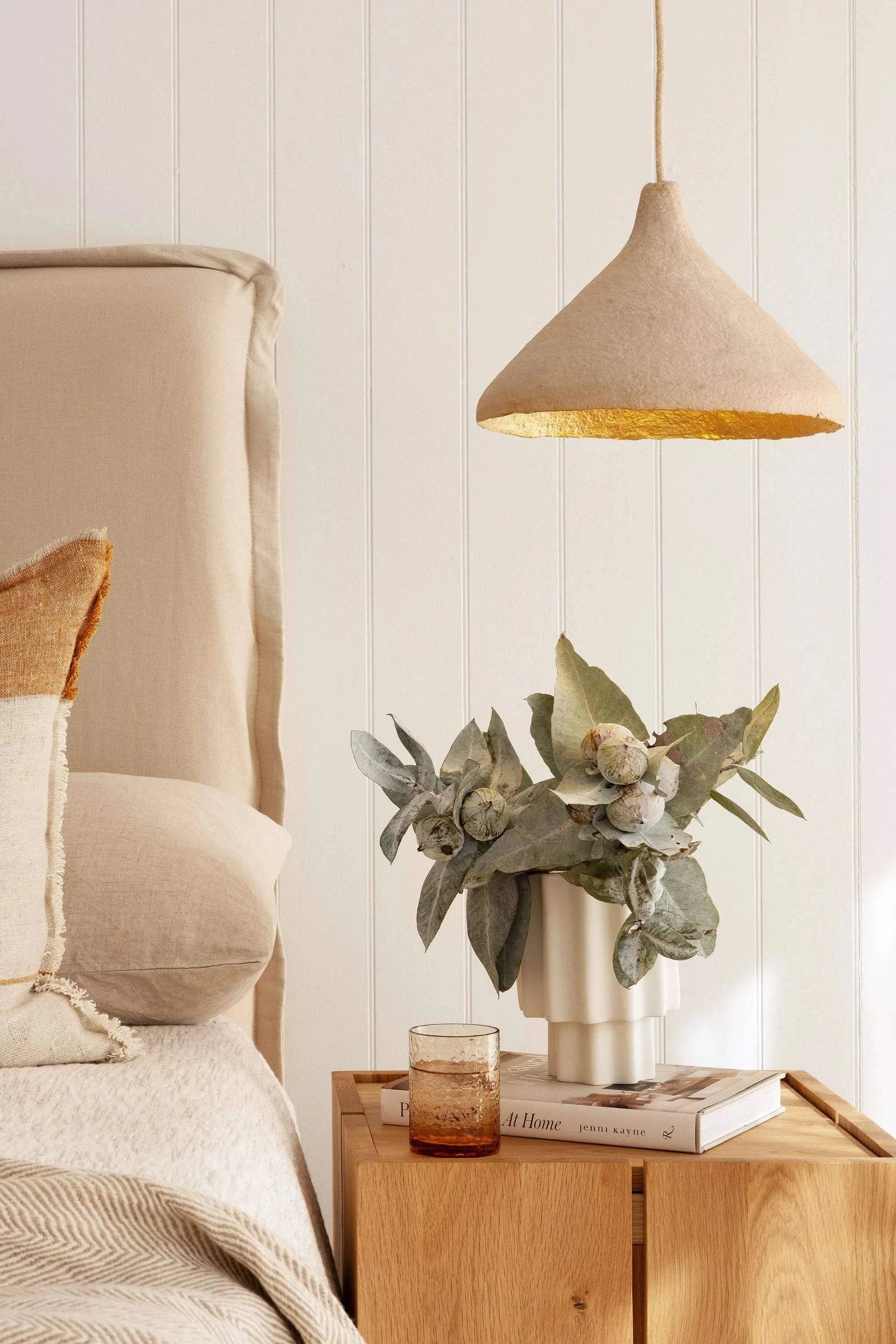 Her Hands - Classic Cone Pendant Light with scalloped edge, handmade from recycled magazines, hanging in a cozy bedroom setting.