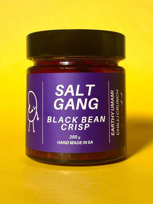 Salt Gang Black Bean Chilli Crisp in glass jar with purple label on yellow background.