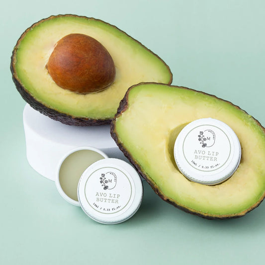 Melvory Avo Lip Butter in a tub with fresh avocado, natural lip balm for dry lips.