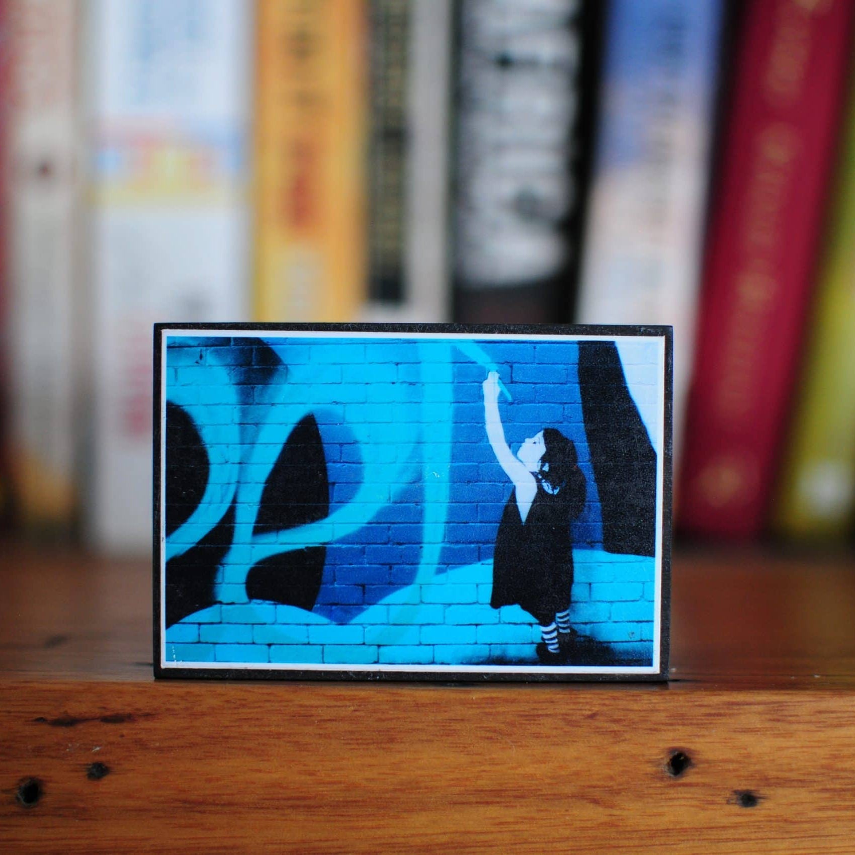 Photo Blocks - Blue Print (Melbourne) displayed on a wooden surface with a child reaching up against a blue brick wall background.