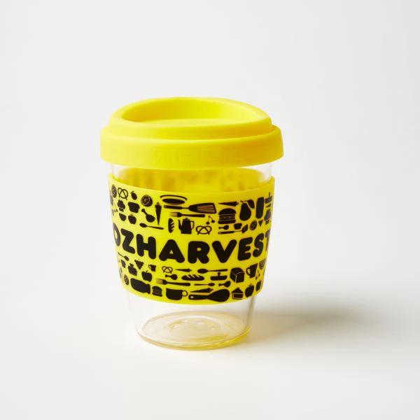 Oz Harvest reusable hand-blown glass coffee cup with yellow lid.